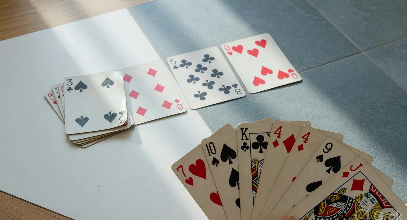 A discard row and a fan of cards on a slate and white table