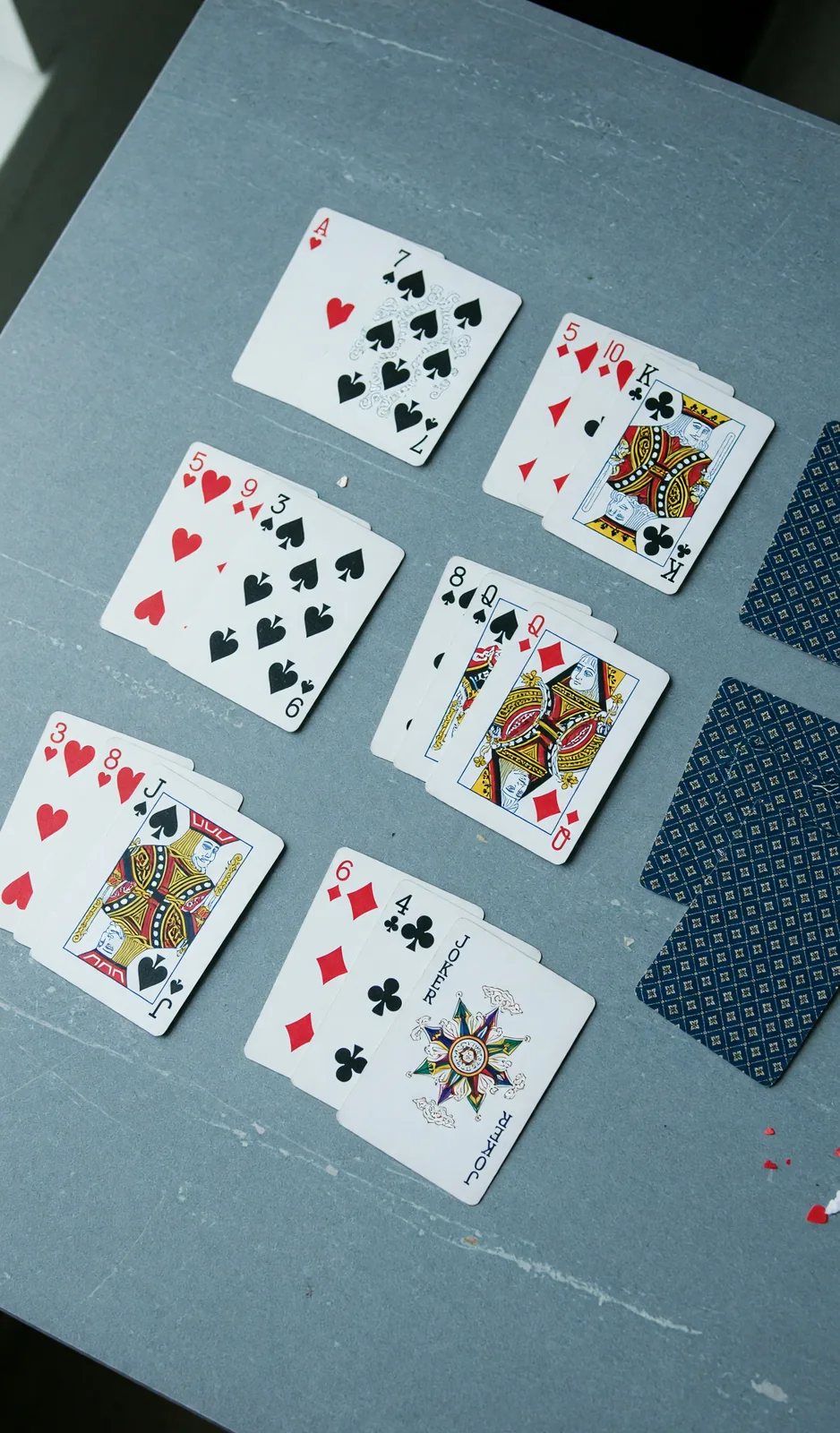 Overhead still of a 13-card rummy hand on a slate table